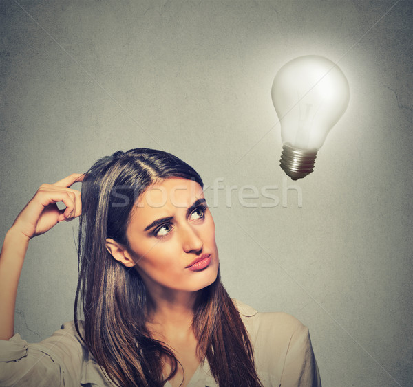 beautiful girl woman thinks looking up at bright light bulb Stock photo © ichiosea