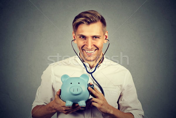 Happy successful man listening to piggy bank with stethoscope  Stock photo © ichiosea