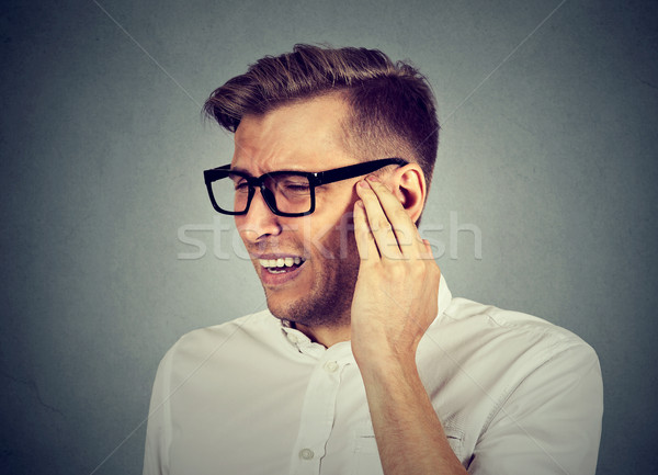 Tinnitus. Sick man having ear pain touching painful head  Stock photo © ichiosea