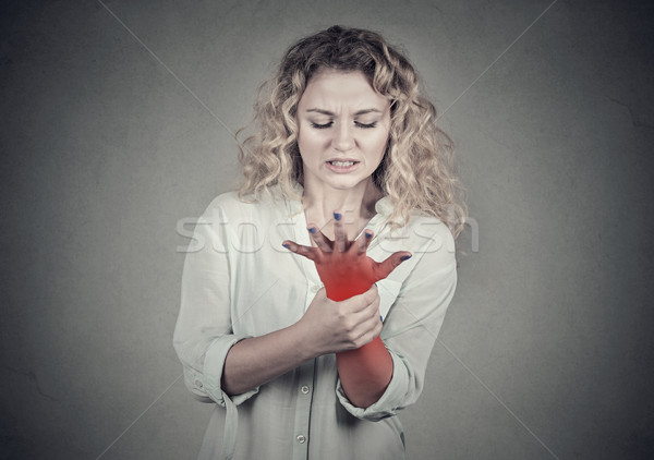 Woman holding painful wrist. Sprain pain location in red Stock photo © ichiosea