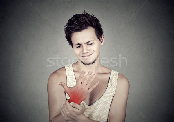 Junger Mann halten schmerzhaft Handwurzel isoliert grau Stock foto © ichiosea