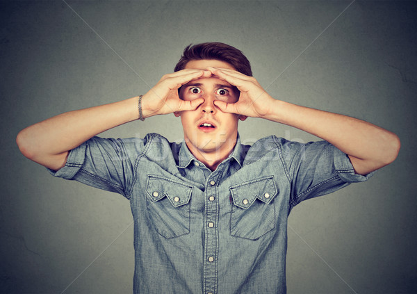 stunned curious man looking through fingers like binoculars searching future  Stock photo © ichiosea