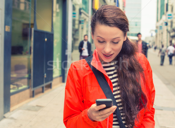 Beautiful young woman walking on a city street and using her mobile phone Stock photo © ichiosea