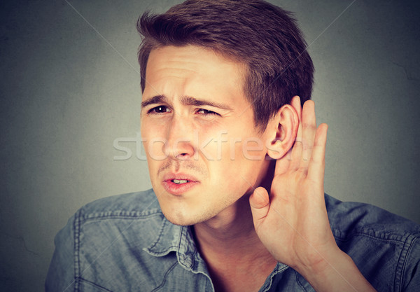 Stock photo: hard of hearing man placing hand on ear asking someone to speak up 