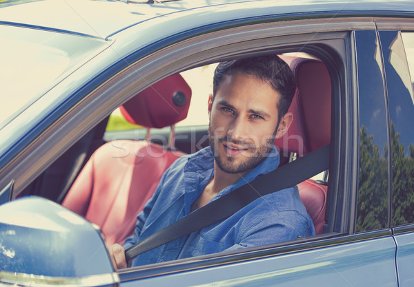 Portrait of handsome guy inside car putting on a safety belt Stock photo © ichiosea