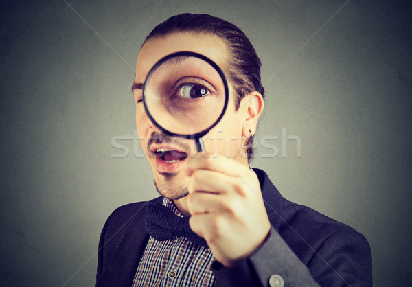Curious young business man looking through a magnifying glass  Stock photo © ichiosea