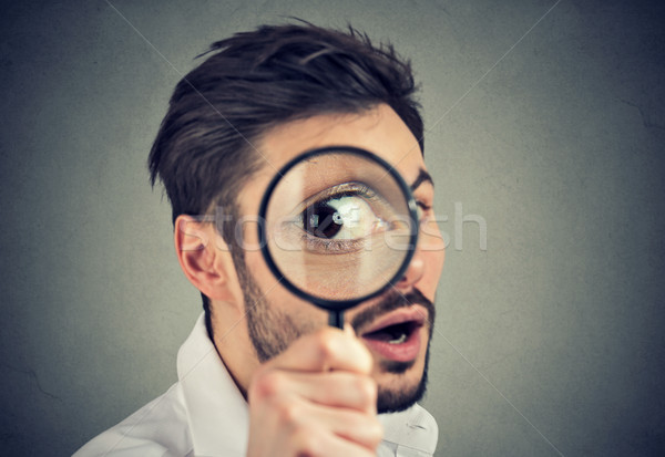 Curious man looking through a magnifying glass  Stock photo © ichiosea