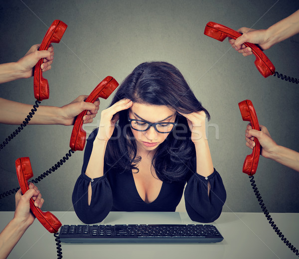 Stock photo: Stressed business woman working on computer overwhelmed by too many phone calls