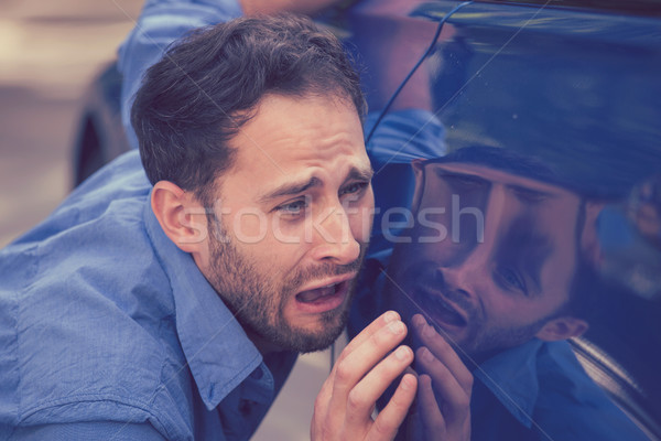 Upset man looking at scratches and dents on his car outdoors Stock photo © ichiosea