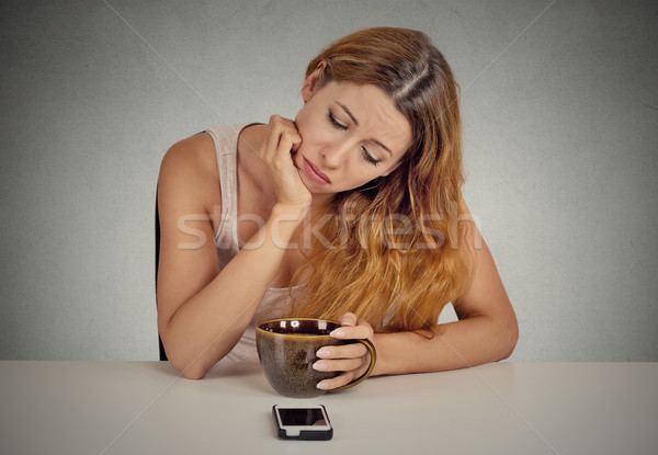 Sad woman sitting at table looking at mobile phone Stock photo © ichiosea