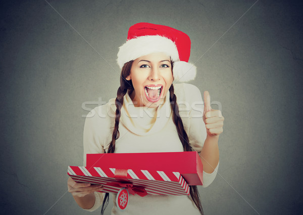 woman wearing santa claus hat opening gift box showing thumbs up Stock photo © ichiosea