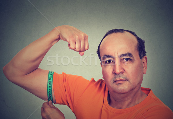 Man flexing his muscle measuring his biceps. Fitness goal achievement result  Stock photo © ichiosea