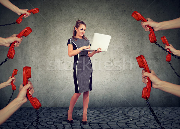 beautiful businesswoman with laptop surrounded by many hands with phone headsets  Stock photo © ichiosea