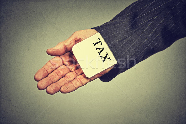 man hand hiding tax card in a sleeve of a suit. tax evasion economy concept Stock photo © ichiosea