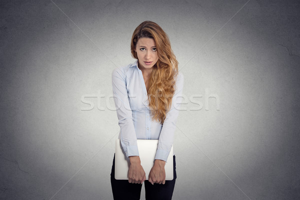 Stock photo:  Insecure worried young woman holding laptop feels awkward