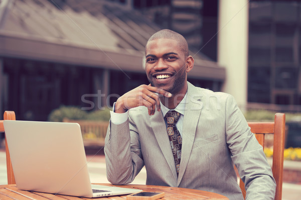 Cheerful business man sitting at table with laptop outside corporate office  Stock photo © ichiosea