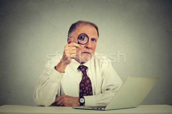 Serious business man in glasses skeptically looking through magnifying glass Stock photo © ichiosea