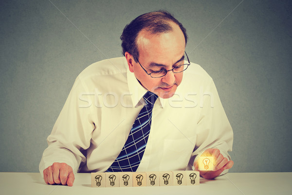 Middle aged business man sitting at table desk with yellow bright light bulb idea Stock photo © ichiosea
