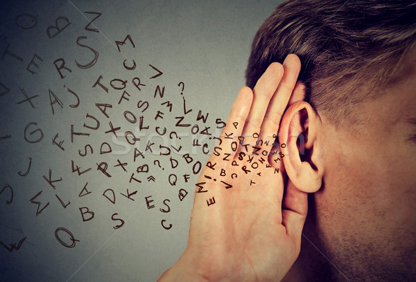 man holds hand near ear listens carefully alphabet letters flying in  Stock photo © ichiosea