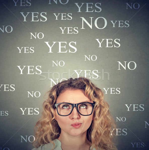 Stock photo: Skeptical woman in glasses with yes no choice looking up 