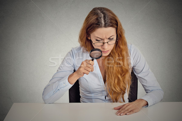 business woman with glasses skeptically looking through magnifying glass at table Stock photo © ichiosea