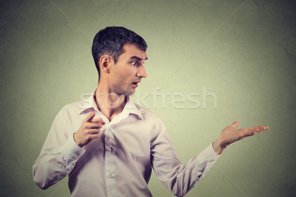 young man looking to side while pointing at you camera, surprised Stock photo © ichiosea