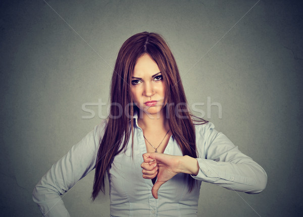 Unhappy woman giving thumbs down gesture looking with negative expression  Stock photo © ichiosea