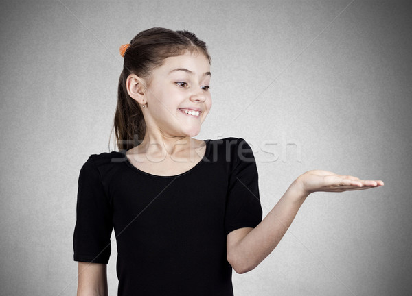 Stock photo: Young smiling girl gesturing to space at right 