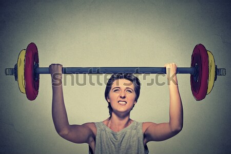 Happy strong young man lifting barbell above head with two hands Stock photo © ichiosea