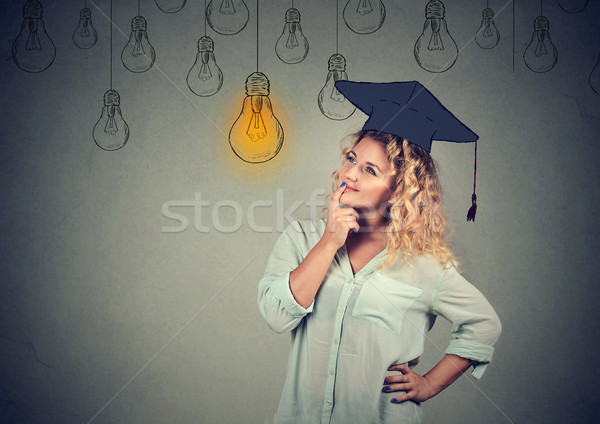 Thoughtful graduate student in cap gown looking up at light bulb Stock photo © ichiosea