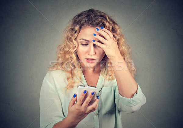 Upset woman holding cellphone disgusted with message she received  Stock photo © ichiosea