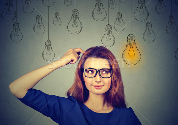 Stock photo: woman in glasses looking up light idea bulb above head 