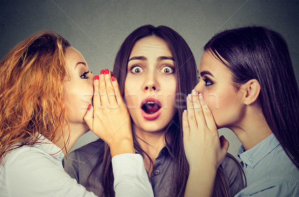 Three young women telling whispering a secret gossip each other in the ear  Stock photo © ichiosea
