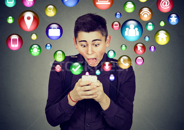 Shocked man using smartphone application icons flying out of cellphone Stock photo © ichiosea