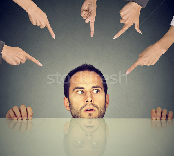 Scared man young employee hiding under the table being accused by many people who point fingers at h Stock photo © ichiosea