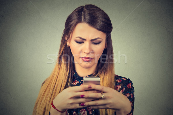 Upset unhappy woman holding cellphone. Sad looking girl texting on smartphone  Stock photo © ichiosea