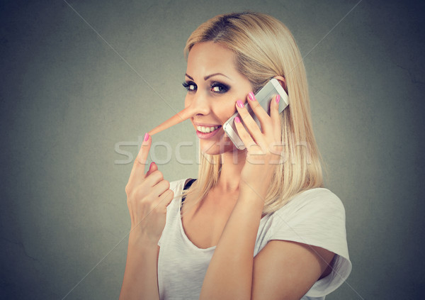 Stock photo: Happy young liar woman with long nose talking on mobile phone 