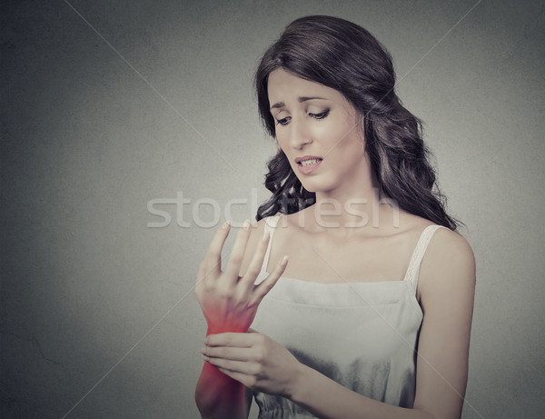 Young woman holding her painful wrist. Negative face expression Stock photo © ichiosea