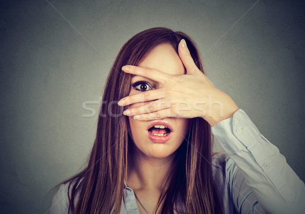 Afraid woman peeking through her fingers Stock photo © ichiosea
