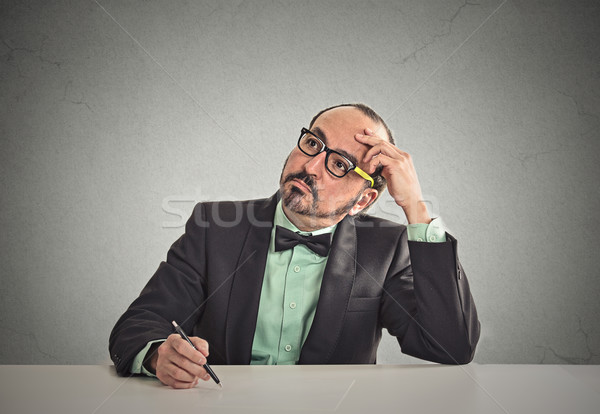 Stock photo: teacher sitting at table scratching his head thinking