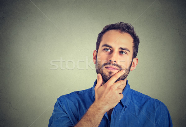 Stock photo: Happy young man thinking daydreaming looking up isolated on gray wall background 
