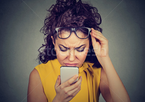 woman with glasses having trouble seeing cell phone vision problems Stock photo © ichiosea