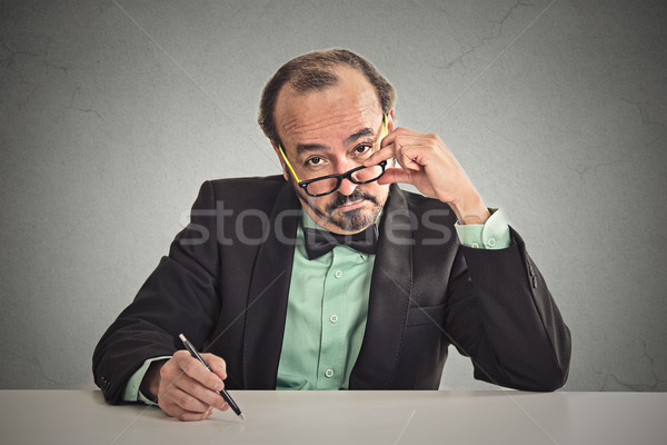 man with glasses skeptically looking at you sitting at his desk  Stock photo © ichiosea