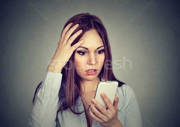 Upset woman looking at cellphone worried with message she received Stock photo © ichiosea