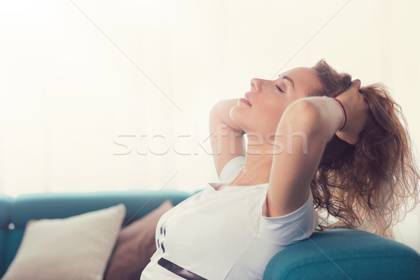 Relaxed young woman sitting on a couch daydreaming  Stock photo © ichiosea