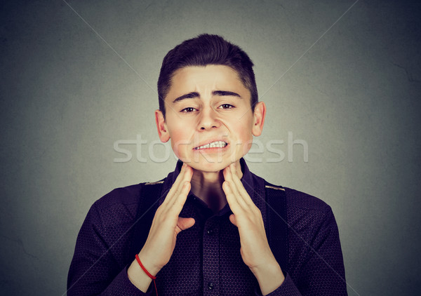 Stock photo: Sick young man having pain touching his neck 