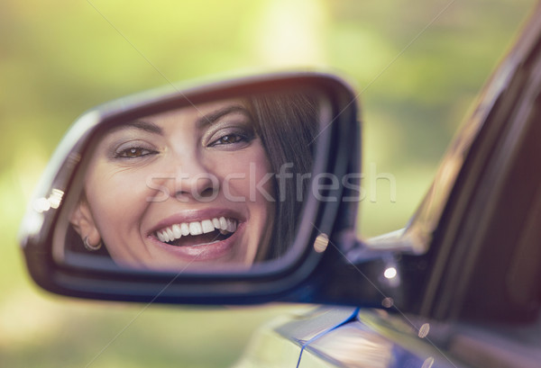 Happy woman driver looking in car side view mirror laughing  Stock photo © ichiosea