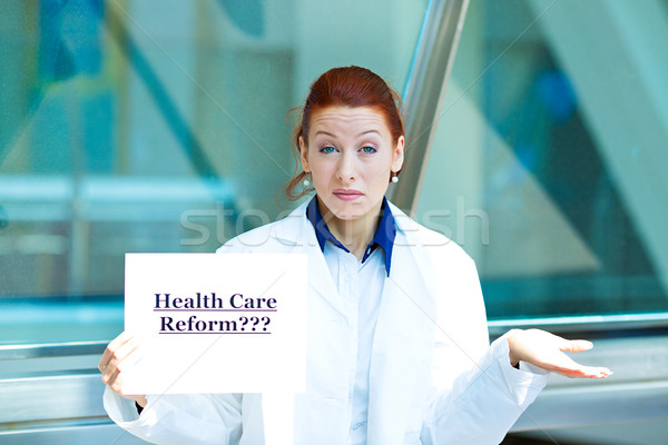 Confused doctor holding health care reform???sign Stock photo © ichiosea