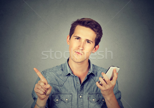 Stock photo: man with cell phone showing no, don't, attention with finger gesture