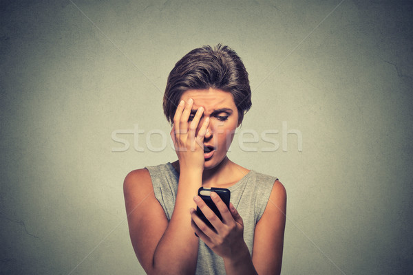 stressed woman holding cellphone disgusted shocked with message she received Stock photo © ichiosea